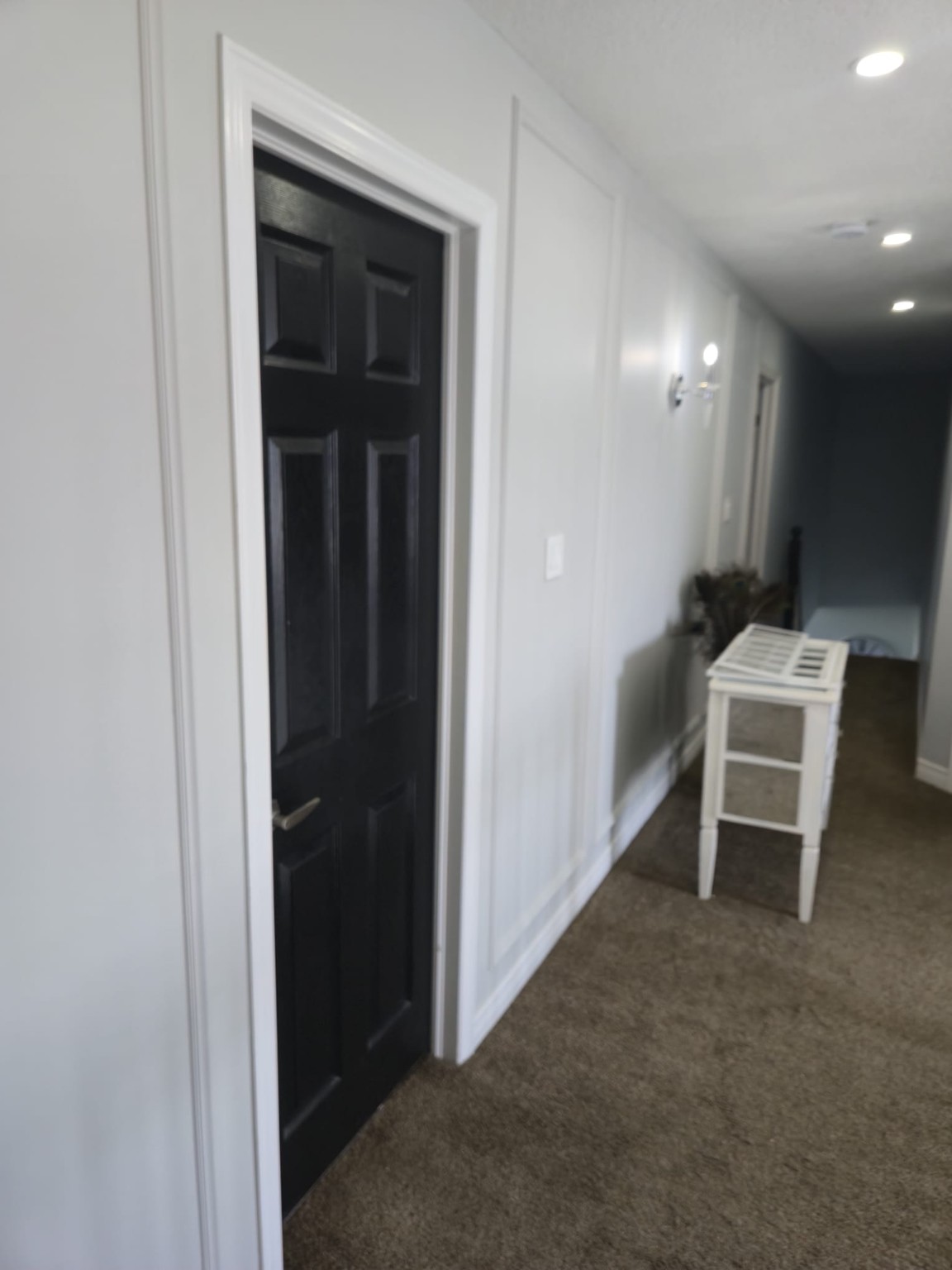 Hallway with smooth grey walls, white trim and a refinished black interior door