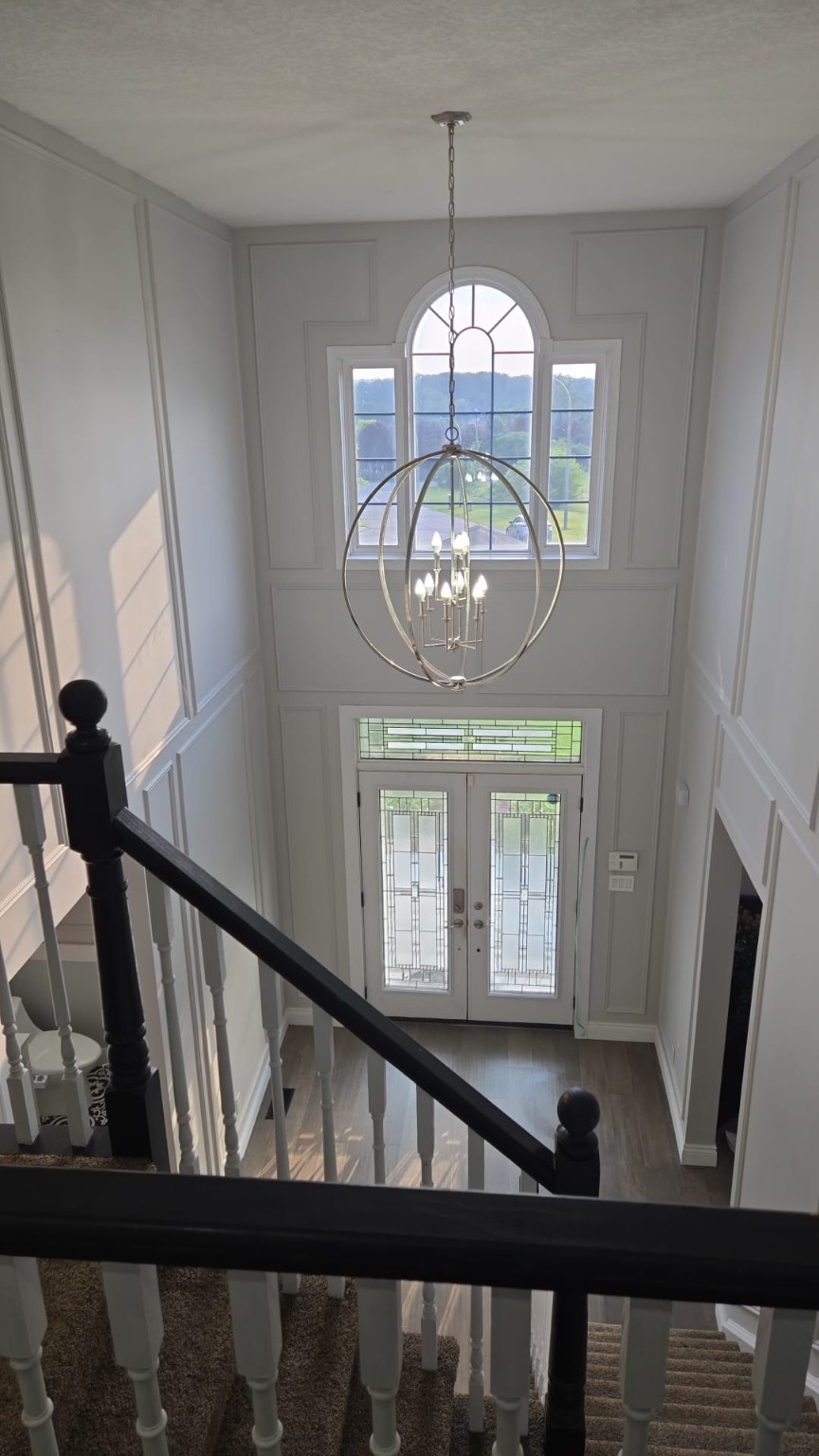 Two-storey foyer with freshly painted grey walls, white wainscoting and a black staircase