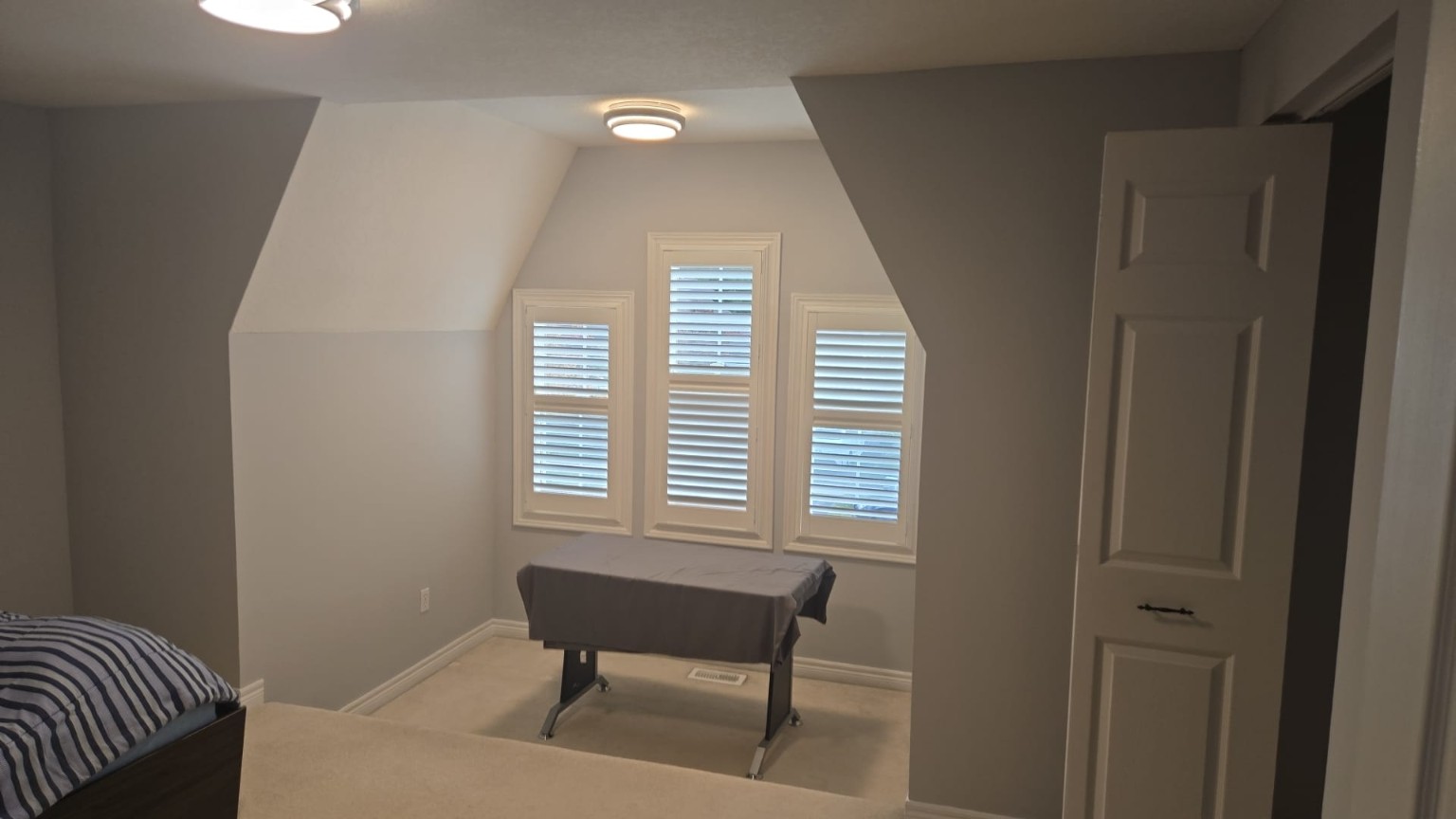 Bedroom with freshly painted walls around a shuttered bay window