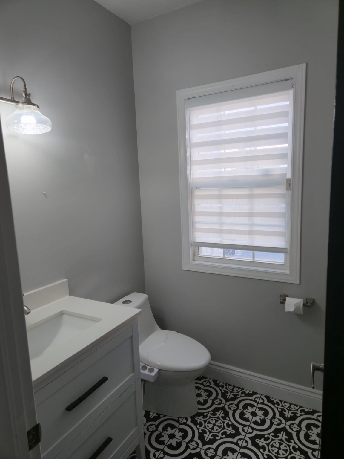 Bathroom with freshly painted grey walls, white vanity and patterned tile floor